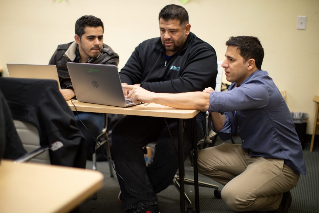 Dunder Data students and professor looking on a laptop