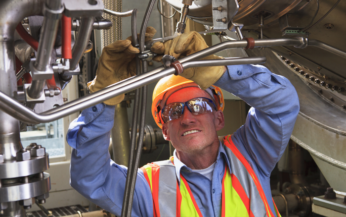 employee performing maintenance with safety googles and safety vest
