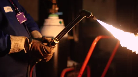 A man wearing gloves using acetylene torch