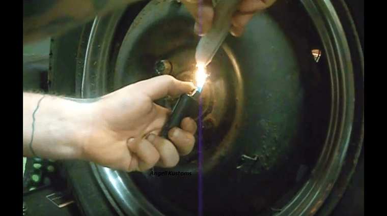 A man lighting up a candle wax with a lighter near lug nuts